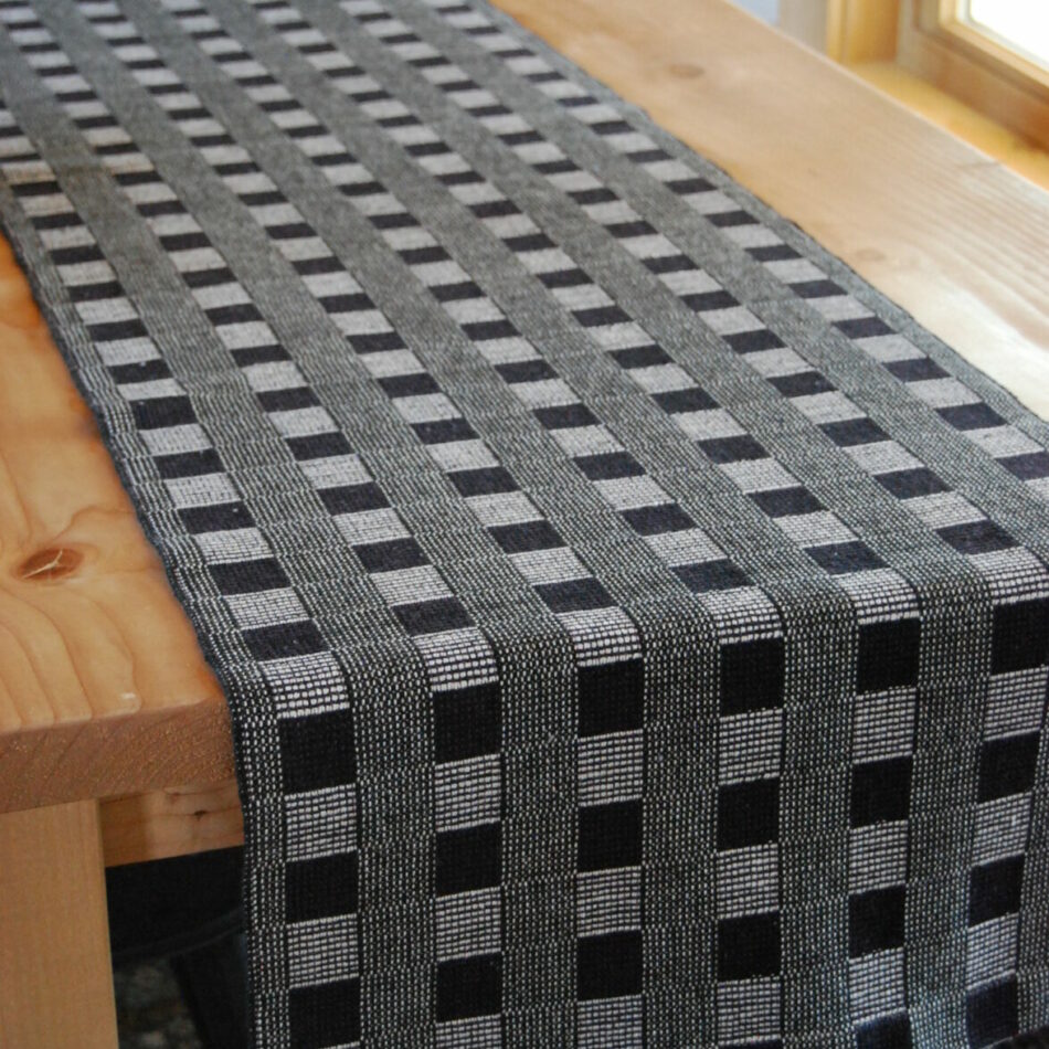 Black and white handwoven table runner on wood table